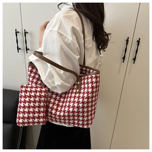 Close-up of red and white houndstooth woven tote bag with brown leather handles and small pouch