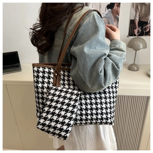 Model wearing a houndstooth tote bag with a small pouch in a bright office setting
