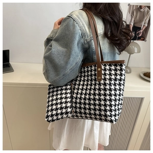 Detail of houndstooth tote bag set with brown leather straps and matching small pouch