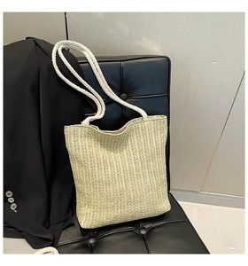Close-up of straw woven tote bag featuring vertical texture and white cotton rope handle