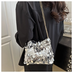 Detail of silver sequin crossbody bag with gold chain strap on a black shirt