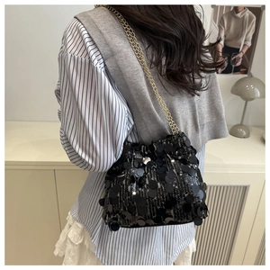 Detail of glossy black sequins and gold chain strap on stylish shoulder bag