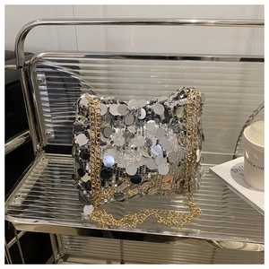 Detail of silver sequin shoulder bag with gold chain strap on a metal display rack