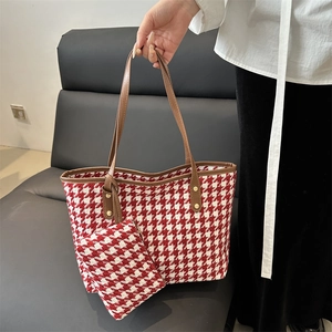 Houndstooth tote bag set with brown leather straps and gold rivets on a grey sofa