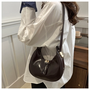 Detailed view of deep coffee crescent shoulder bag with golden metal hardware detail