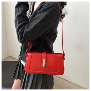 Red leather underarm bag with gold lock shown on model with grey pleated skirt