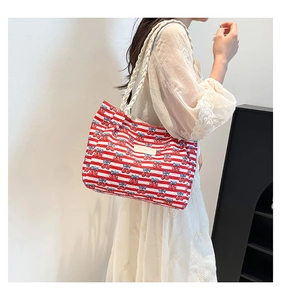 Detail of canvas tote bag featuring red stripes, cherry print, and woven rope handles