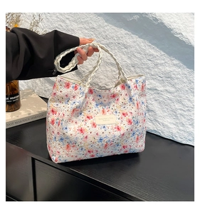 Detail of white floral canvas tote with embossed texture and woven handles