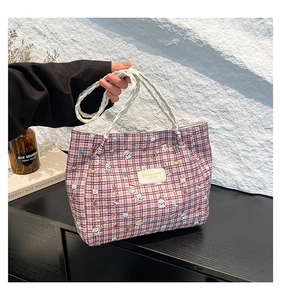 Detail of red and purple checkered tote bag with cute cartoon prints and woven handles