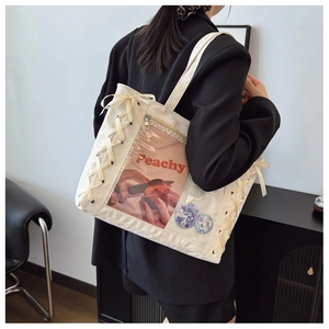 Detail view of white canvas ita bag with clear window and decorative side ribbons