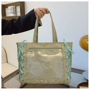 Close-up of light green tote bag with transparent PVC window and blue ribbon details