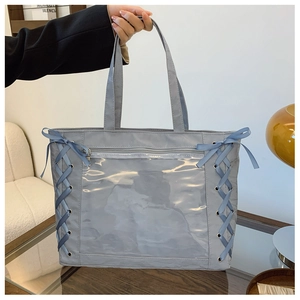 Detail of grey-blue tote bag featuring cross-ribbon lacing and transparent PVC pocket