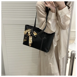 Side view of black leather tote bag with white stitching and floral scarf handle detail