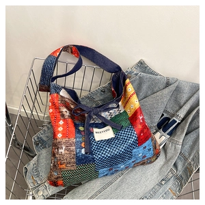 Close-up of ethnic patchwork tote bag featuring denim bow tie and white logo label