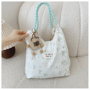 Détails des motifs de lapin et des poignées vert menthe sur un sac cabas en toile crème