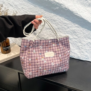Purple plaid tote bag with cartoon dog patterns and white braided handles on a wooden table