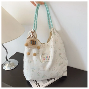 Detailed view of white canvas tote with rabbit print and mint green braided handle