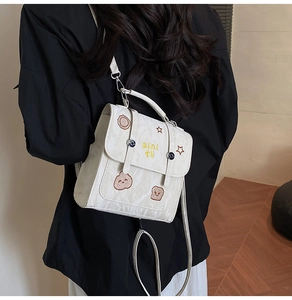 Detail eines weißen Nylon-Minirucksacks mit niedlichen Bären- und Sternstickereien darauf
