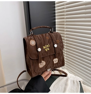 Detail of vintage brown textured backpack featuring cartoon toast and star embroidery