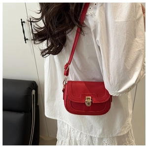 Détail du sac selle en cuir grainé rouge avec boucle dorée porté par un mannequin