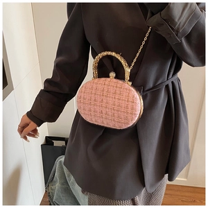 Detailed view of pink tweed evening bag with gold textured handle and crystal ball clasp