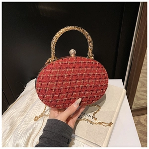 Detail of red tweed evening clutch featuring gold chain strap and ring handle
