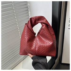 Detailed close-up of dark red woven leather handbag with a unique knot handle design