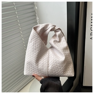 Detail of woven light pink shoulder bag with unique knotted handle and lattice texture