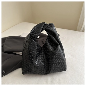 Detail of minimalist black woven leather hobo bag with a signature knotted handle