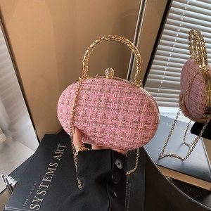 Pink tweed box bag with gold metal handle and chain, shown on a reflective surface