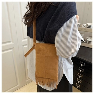 Detail view of dark brown suede crossbody bag with long fringe and bohemian stitching