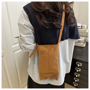 Vue arrière d'un mannequin portant un sac bandoulière en daim marron avec des franges