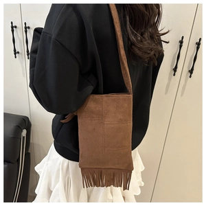 Detailed view of brown suede crossbody bag featuring vintage style fringe decorations