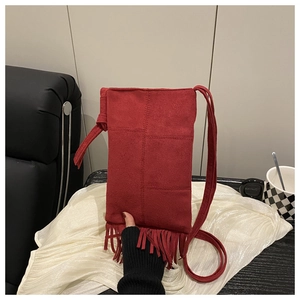Détail d'un sac bandoulière en suédine rouge avec de longues franges bohèmes