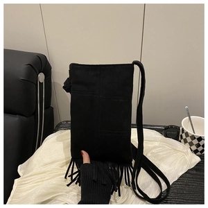 Détail d'un petit sac bandoulière en daim noir avec franges longues et bandoulière fine