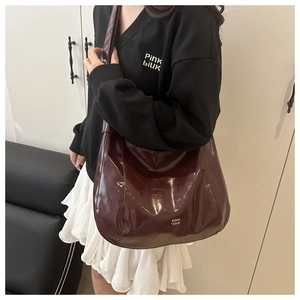 Detail of burgundy patent leather tote bag with high gloss finish and shoulder strap