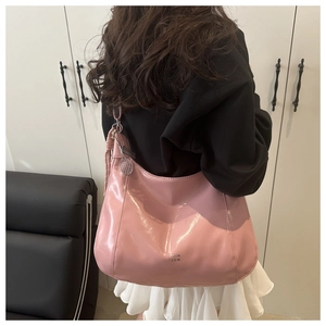 Detail of glossy pink patent leather hobo bag featuring a decorative tennis racket charm