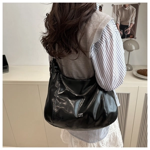 Detail of black glossy hobo bag with white print and crescent moon shape worn by a model