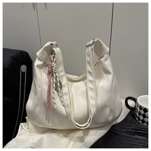 Detail of white soft leather tote bag with unique knot shoulder strap and bicolor charms