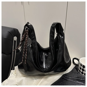 Macro shot of glossy black patent leather tote bag with a mini tennis racket charm