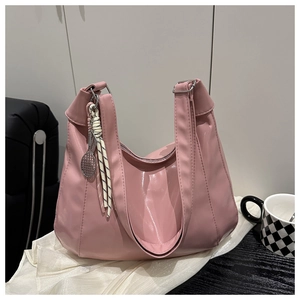 Close-up of pink glossy tote bag with tennis racket charm on white silk fabric