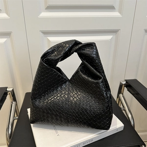 Minimalist black woven leather shoulder bag with a knotted handle and crescent silhouette