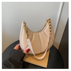Detailed macro of beige crescent bag featuring shell pleated texture and gold chain