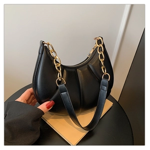 Detail of black crescent shoulder bag with vertical pleats and chunky gold chain strap