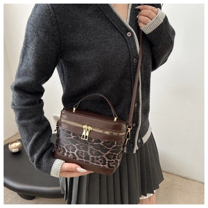 Close-up of leopard print bucket bag with metal double zippers and brown leather trim