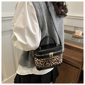 Detail of leopard print bucket bag featuring gold-tone zippers and contrasting leather trim