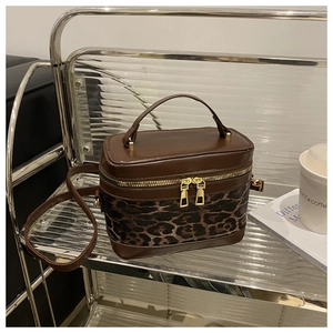 Detail of leopard print bucket bag with brown leather contrast and gold zipper