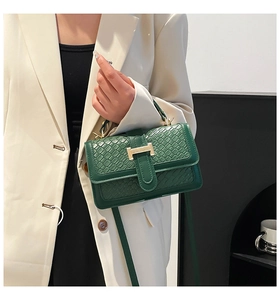 Detail of dark green woven square bag featuring a gold H-clasp and leather texture