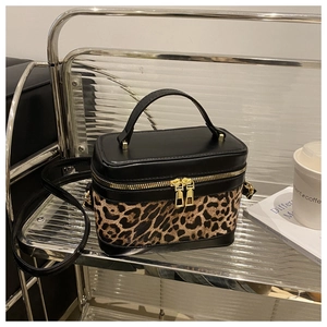 Close-up of leopard print bucket bag with gold zippers and stylish metal shelf background