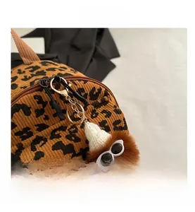Detail of leopard print corduroy crossbody bag with a creative furry monster charm